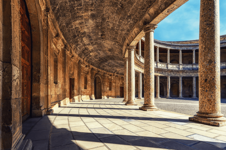 a stone building that has a bench in front of a brick wall