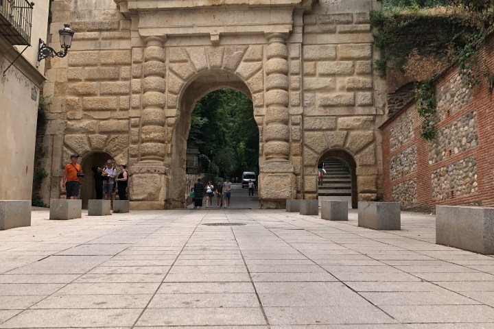 a stone building that has a bench in front of a brick wall