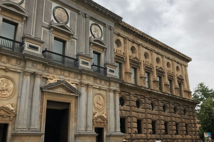 a group of people walking in front of a stone building
